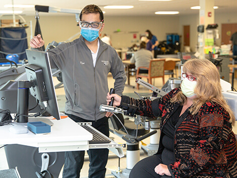 A rehabilitation therapist aids a stroke survivor using the Armeo Spring.