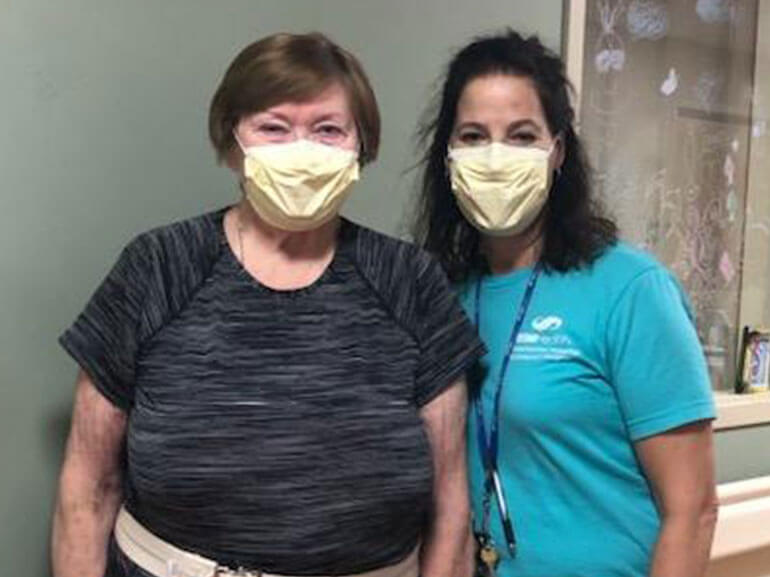 Beatrice Brady standing with her therapist, both wearing masks. 