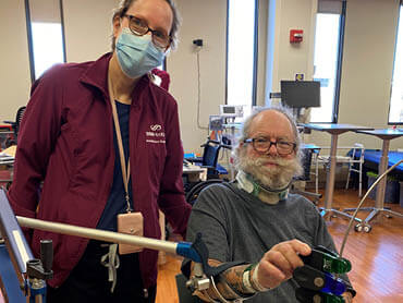 Harold Phillips works with a therapist in the gym while wearing a neck brace.