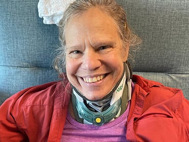 Pamela Petri smiling broadly while wearing a neck brace.