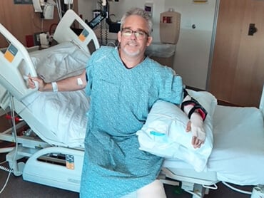 Brian sitting on the edge of his hospital bed.