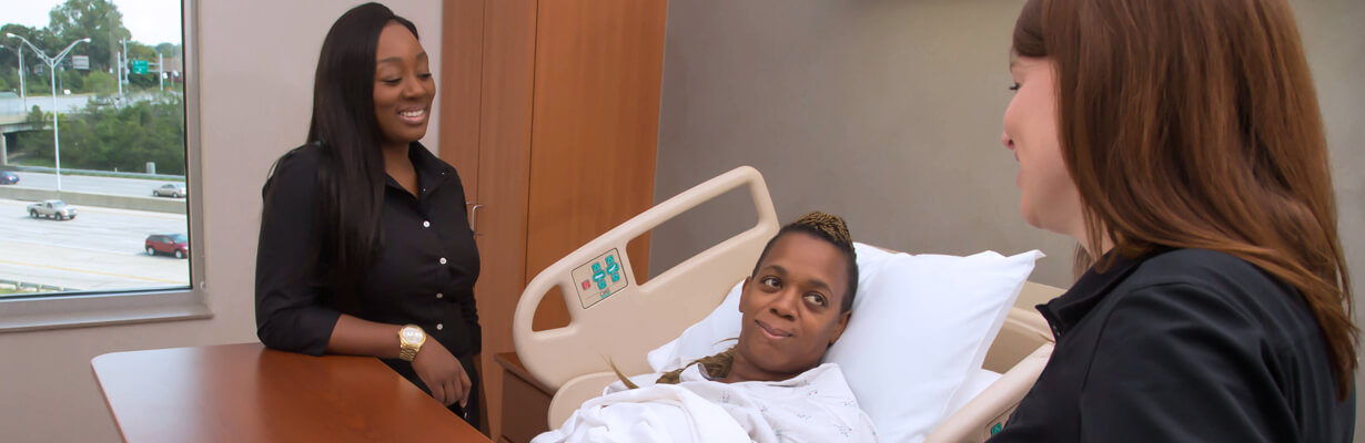 Two therapists standing bedside with recently admitted patient