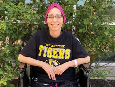 Patient Debbie Lane, sitting in a wheelchair, smiling.