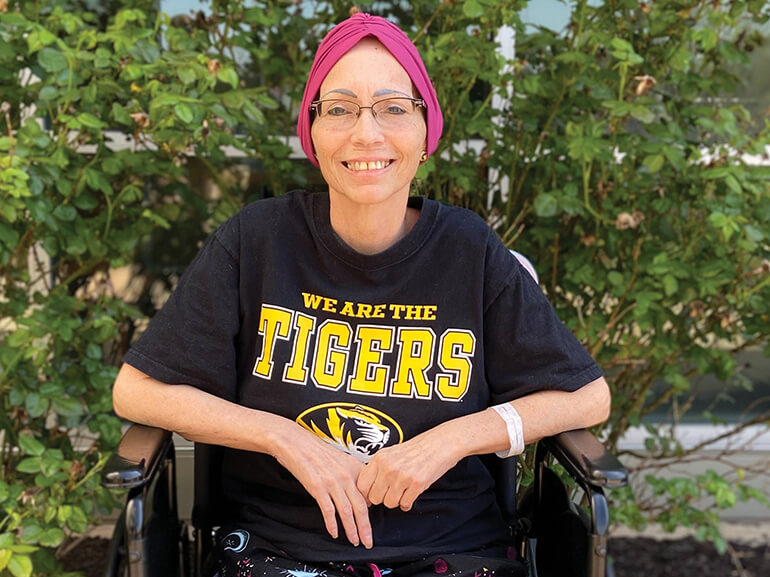 Patient Debbie Lane, sitting in a wheelchair, smiling.