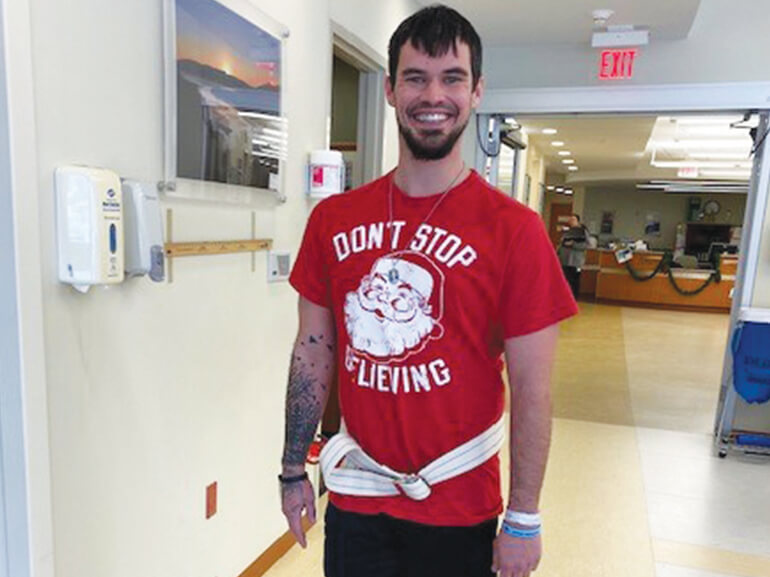 Chris Crocker, spinal cord injury patient, standing and smiling.