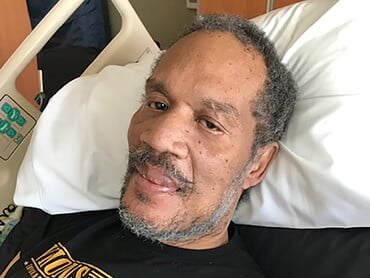 Patient Frederick Sanders lying in a hospital bed.